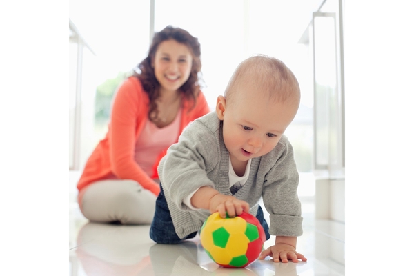 Baby playing with mother in background.